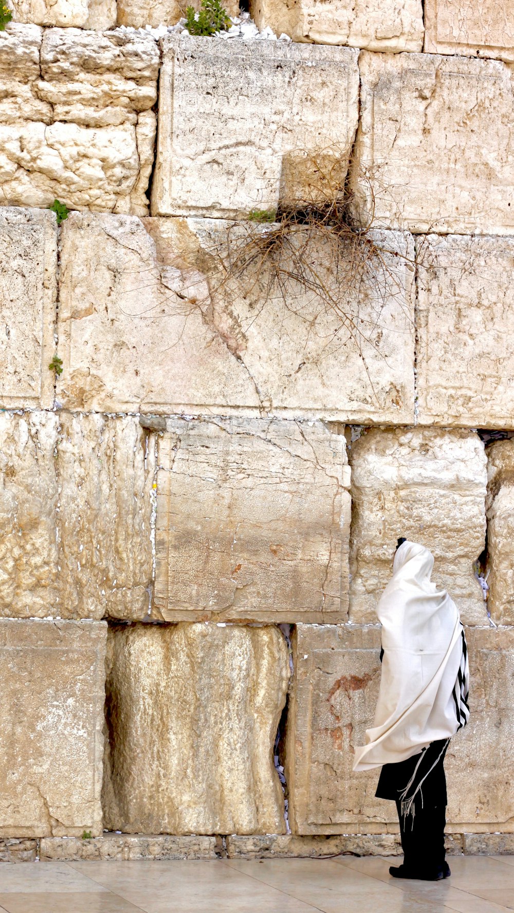 Mujer con hijab blanco de pie junto a un muro de hormigón marrón durante el día