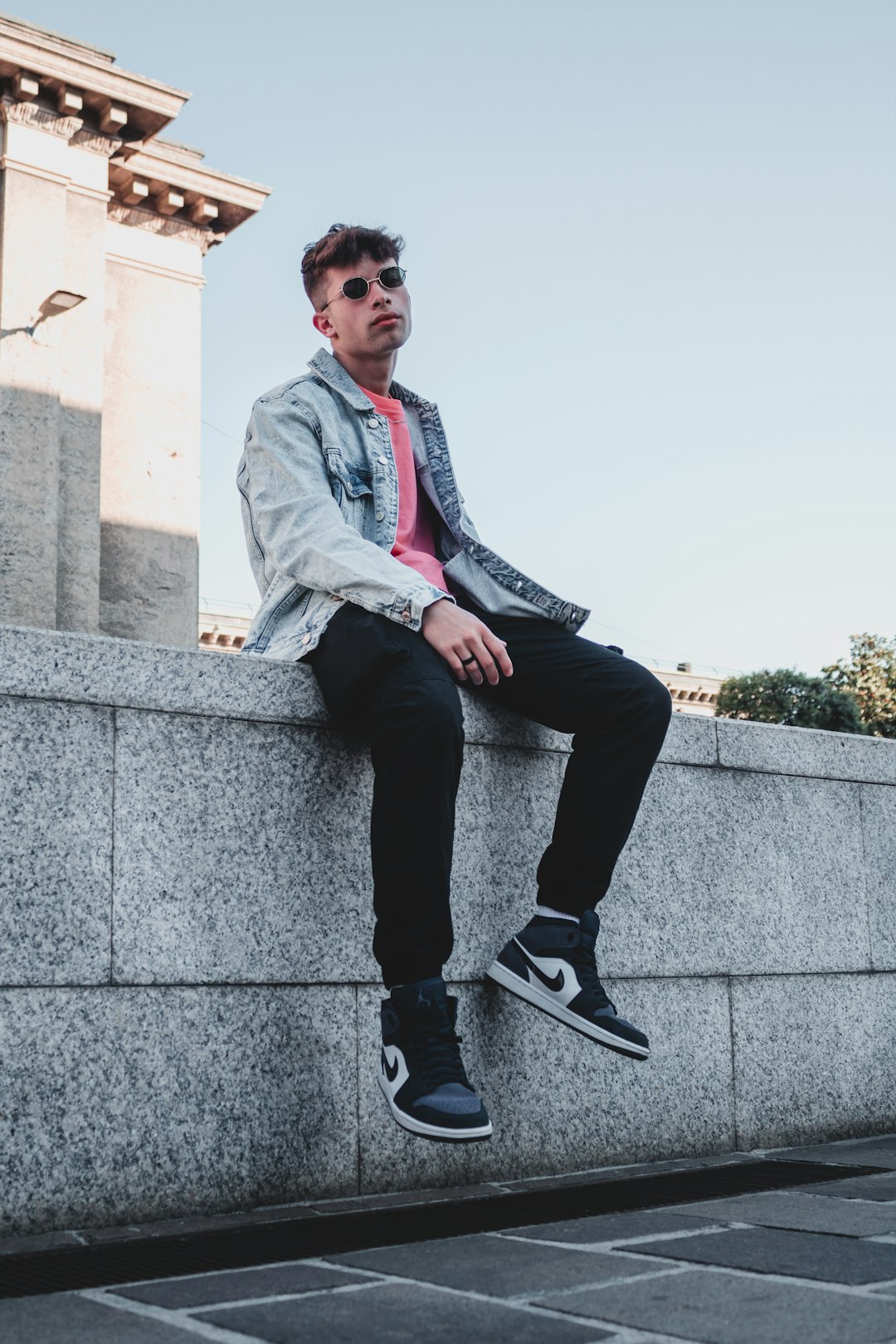 man in gray blazer sitting on gray concrete wall during daytime