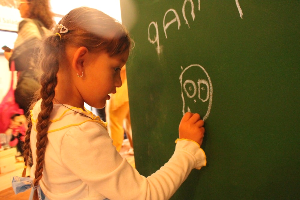 woman in white dress shirt holding green chalk board