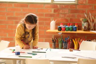 woman in brown jacket writing on white paper