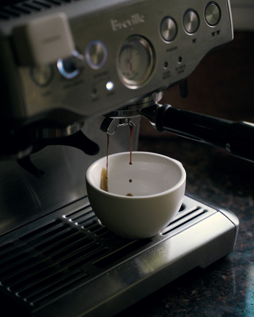 Taza de cerámica blanca en máquina de café espresso negra y plateada