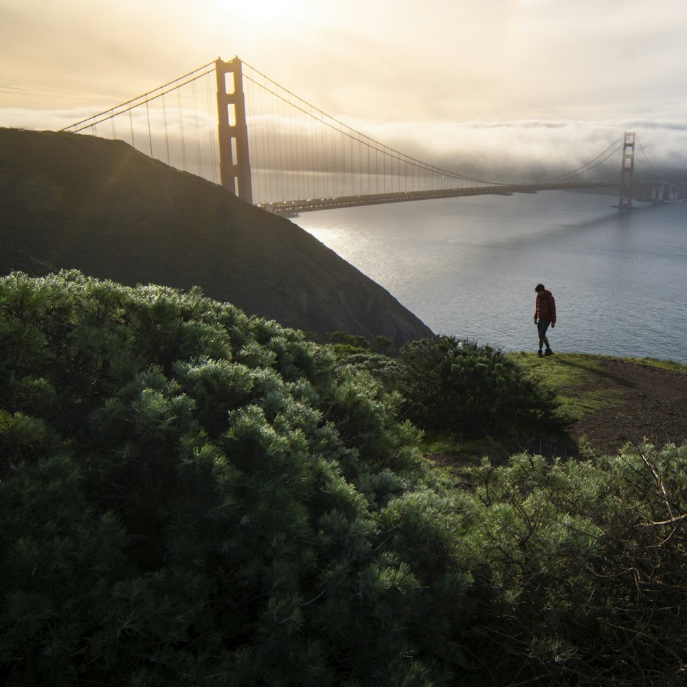 Person, die tagsüber auf grünem Gras in der Nähe der Golden Gate Bridge steht