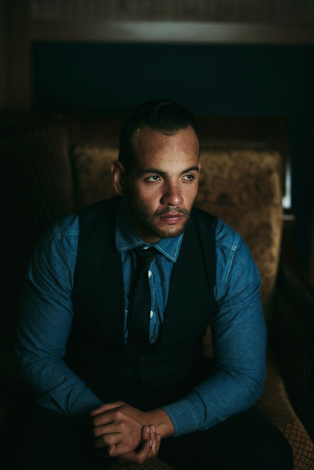 man in blue dress shirt sitting on brown sofa