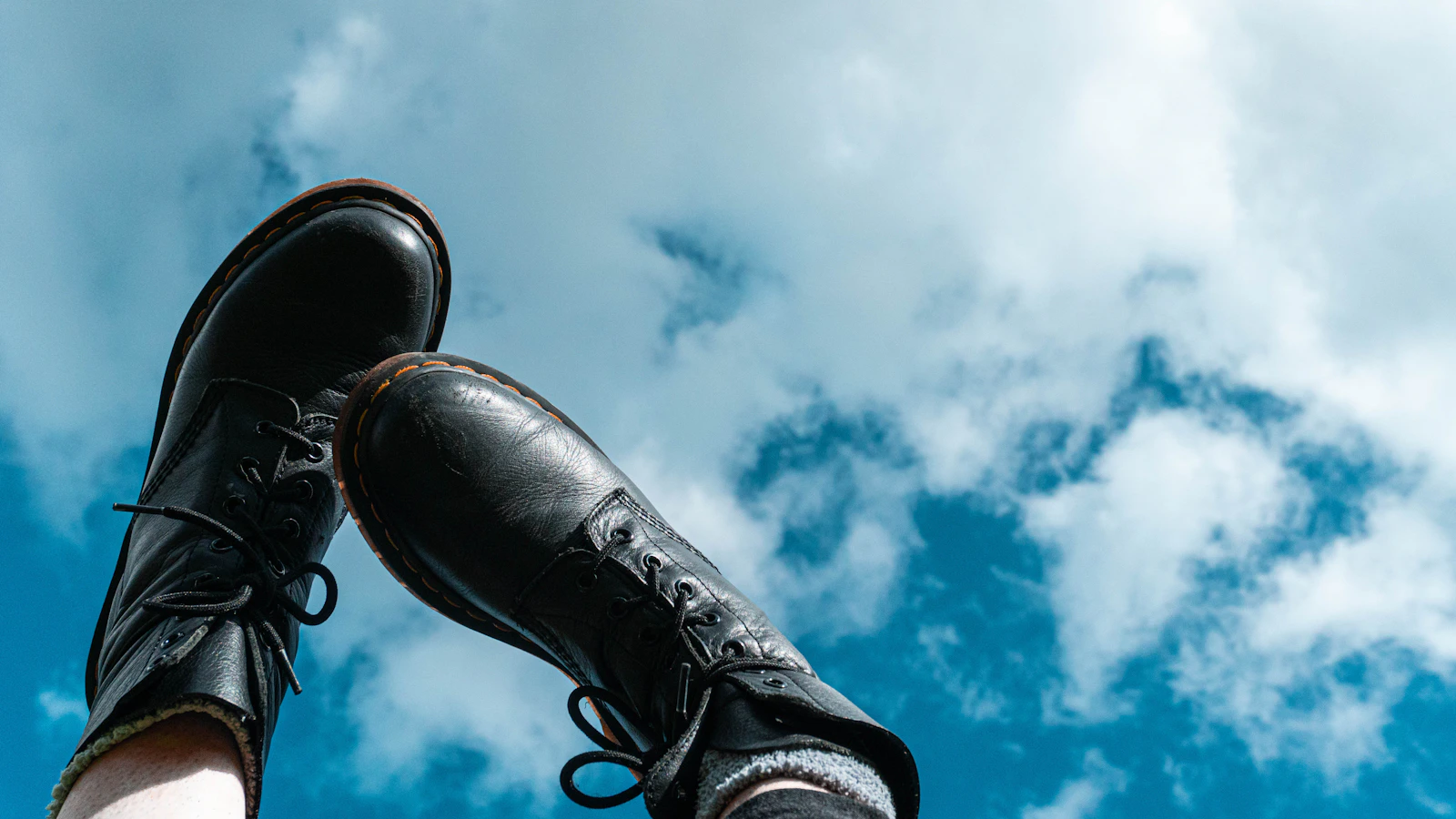Black leather boots against sky