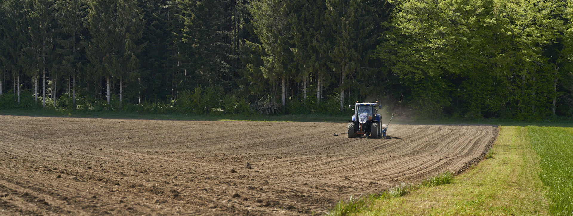blue tractor on brown field during daytime