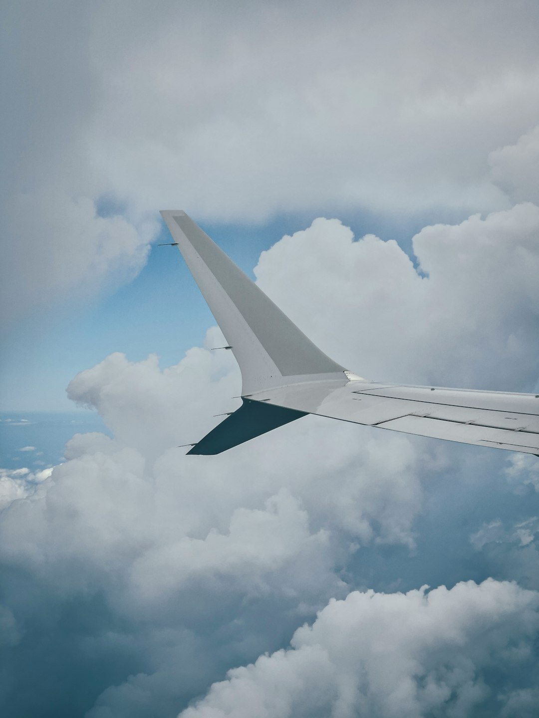 white airplane wing under white clouds during daytime
