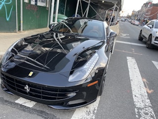 A sleek car wrapped in glossy black vinyl parked on a city street.