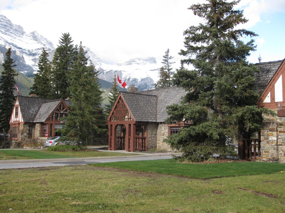 Maison brune et grise près des arbres verts et de la montagne pendant la journée