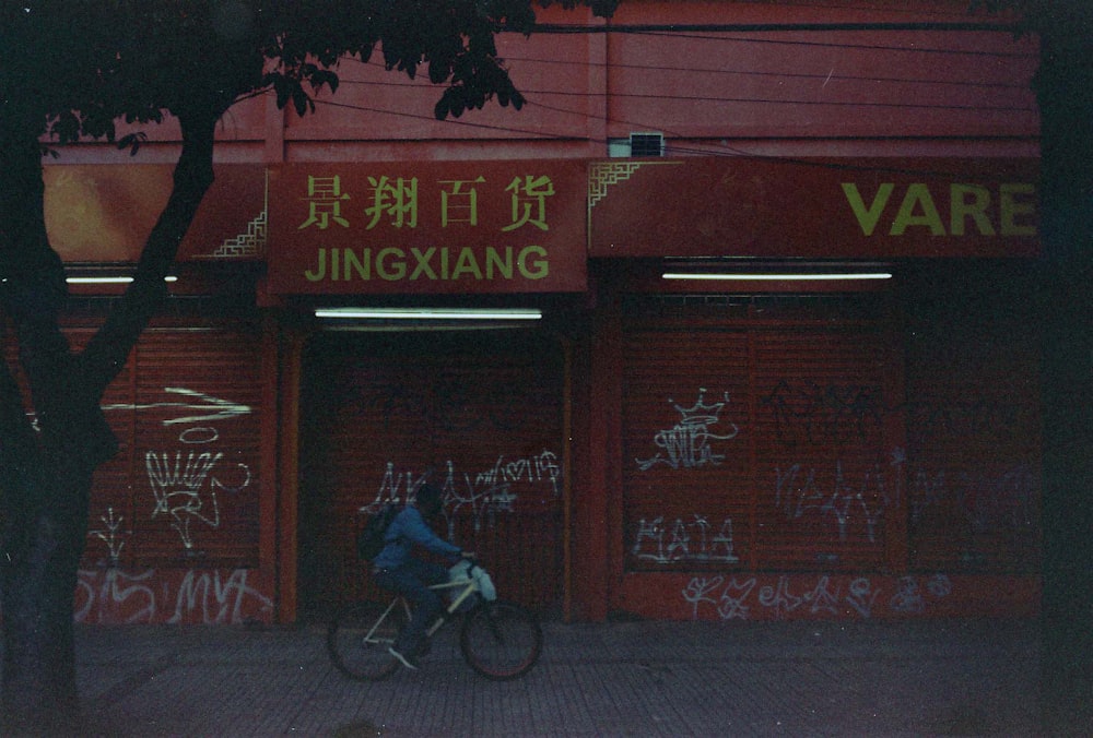 a person riding a bike past a building covered in graffiti
