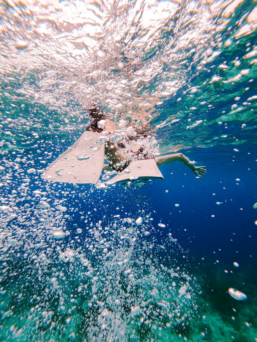 man in black wet suit riding white surfboard in the middle of the sea