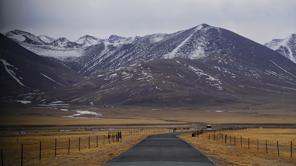 gray concrete road near snow covered mountain during daytime