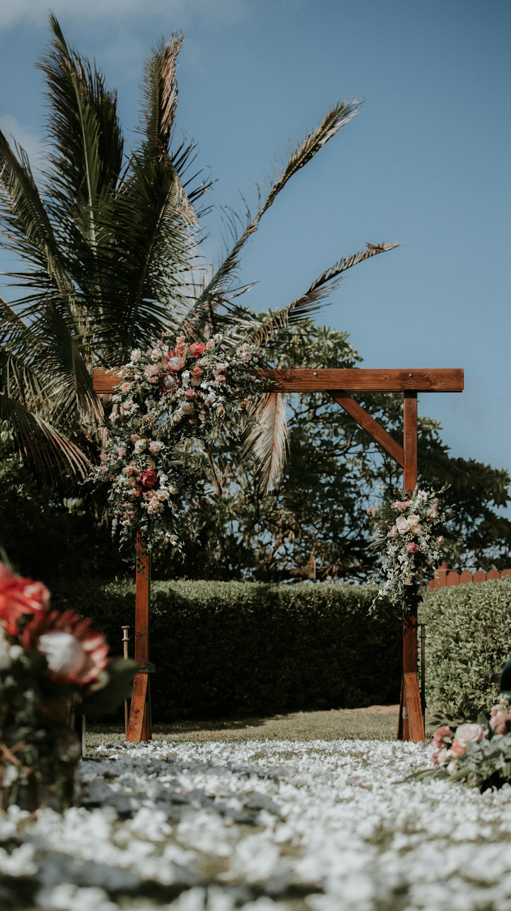 Cruz de madera marrón con flores rojas y blancas