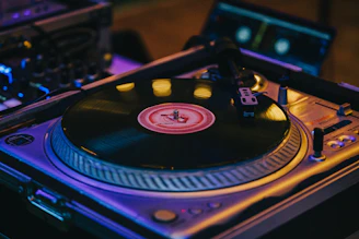 Close-up of a DJ spinning reggae vinyl records with colorful lights.