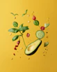 Avocado, basil, corn, cucumber, and chili slices floating against a yellow background
