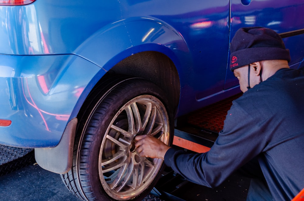 person in black pants standing beside blue car