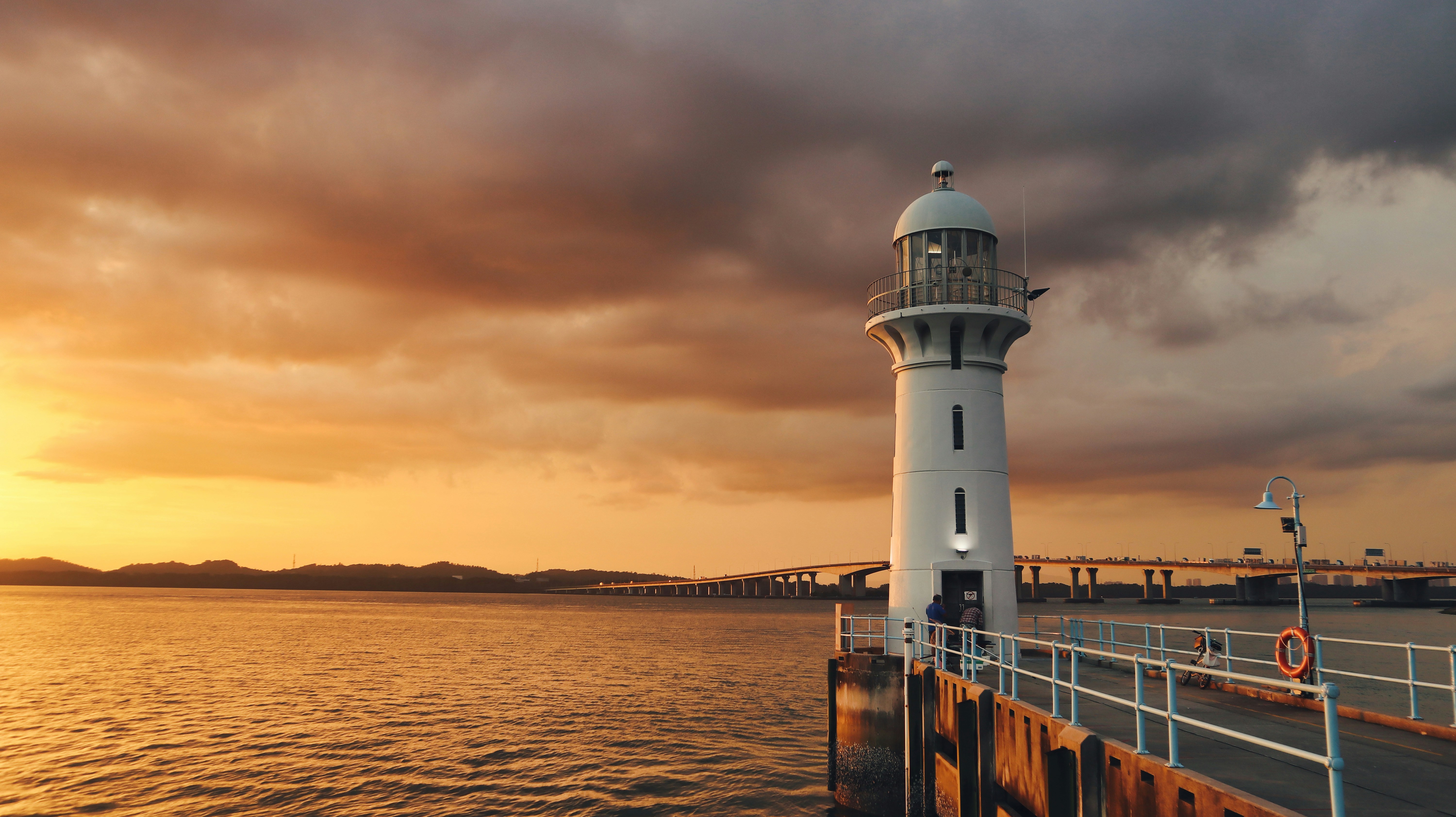 white and black lighthouse near body of water during sunset