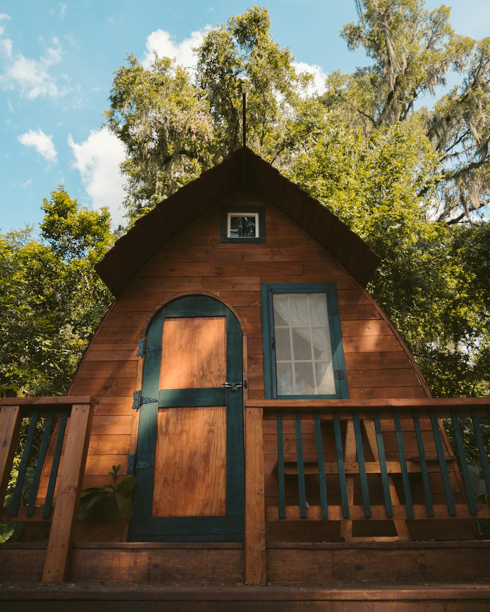 brown wooden house near green tree during daytime