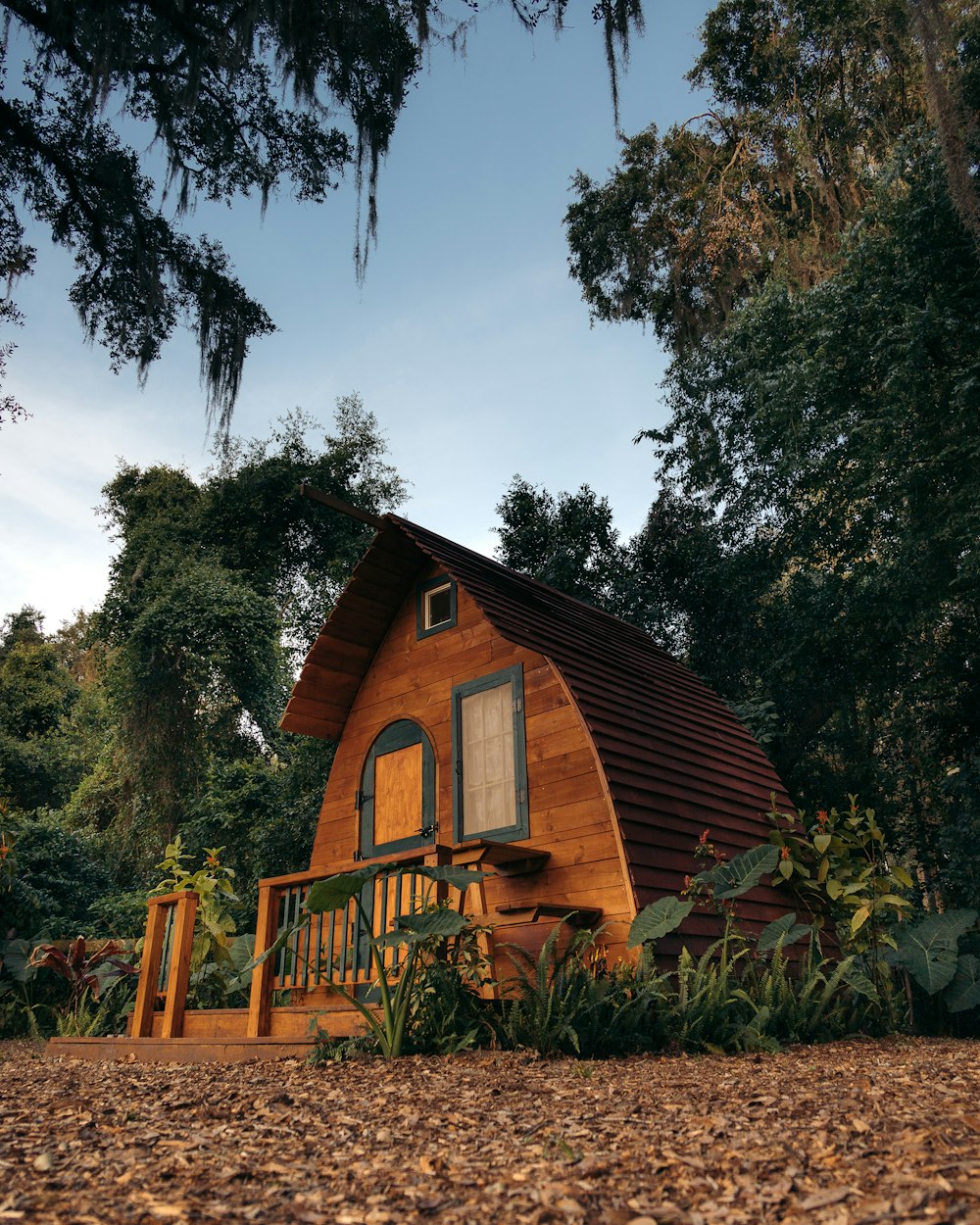 brown wooden house surrounded by green trees under blue sky during daytime