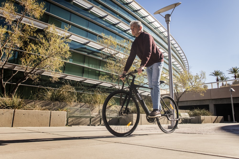 man in red long sleeve shirt and blue denim jeans riding on bicycle