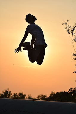 A vibrant photo of a person performing a dynamic calisthenics move outdoors at sunrise.