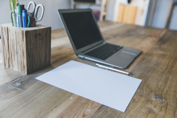 Close-up of legal documents and a pen on a wooden desk with a laptop in the background.