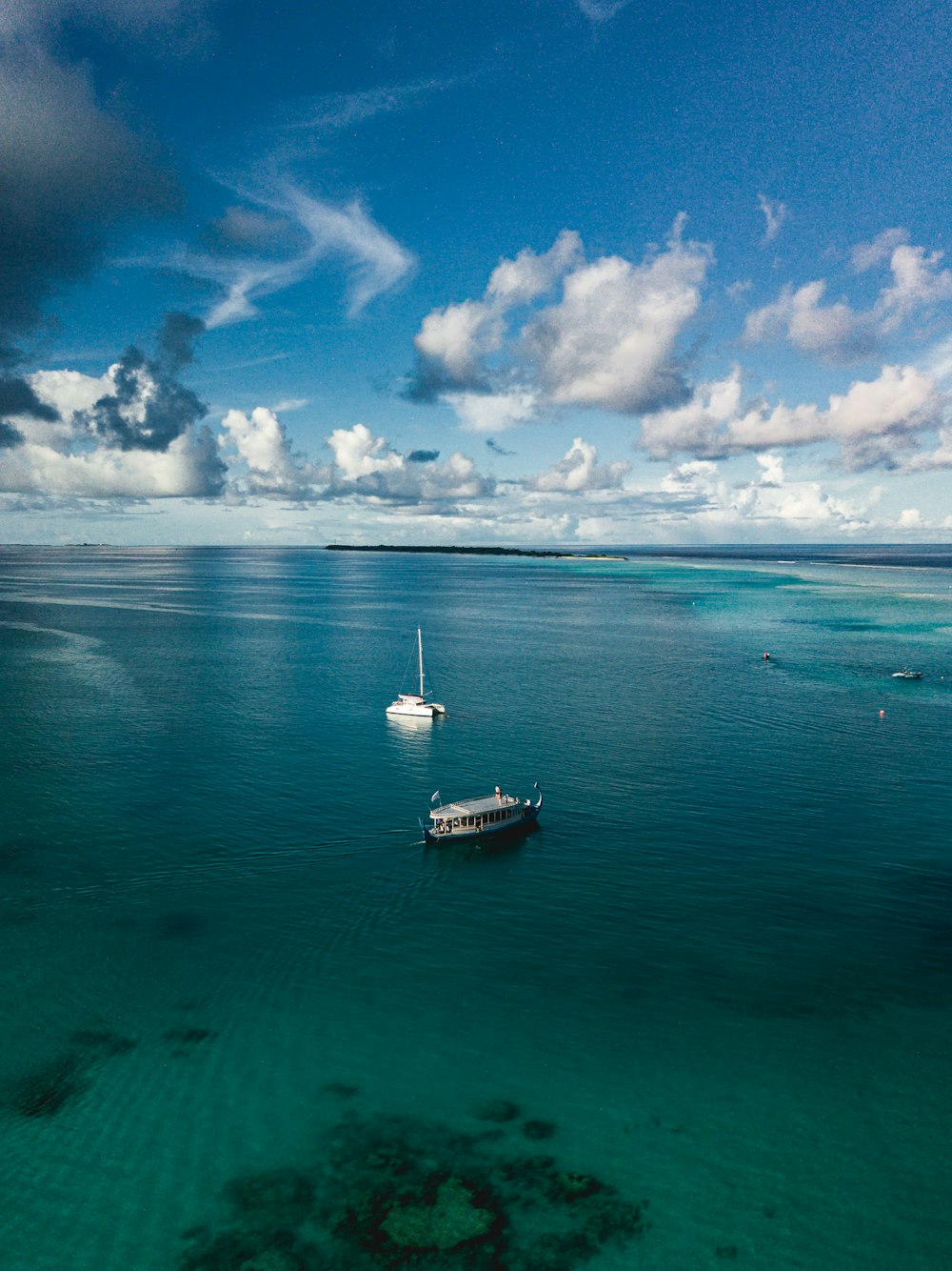 white boat on sea under blue sky and white clouds during daytime