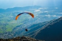 person in black shirt with yellow parachute over the mountains during daytime