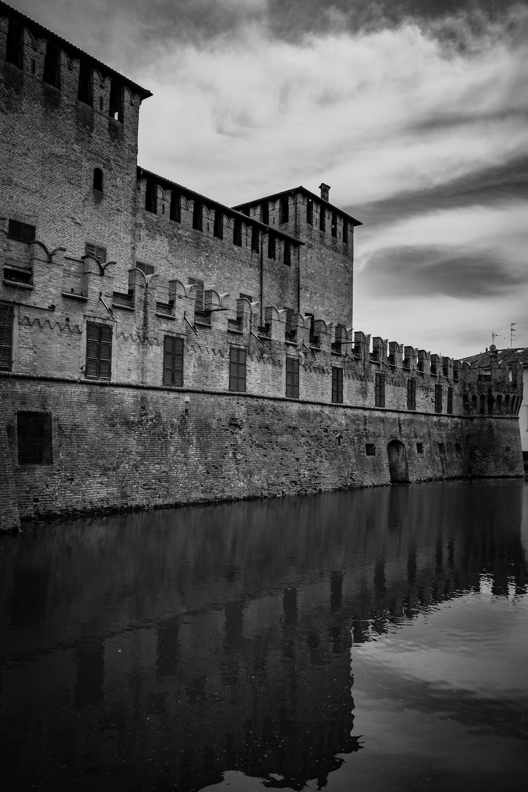 grayscale photo of concrete building near body of water