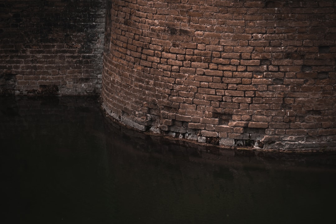 brown brick wall beside body of water