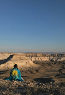 woman in blue and green jacket standing on brown rock formation during daytime