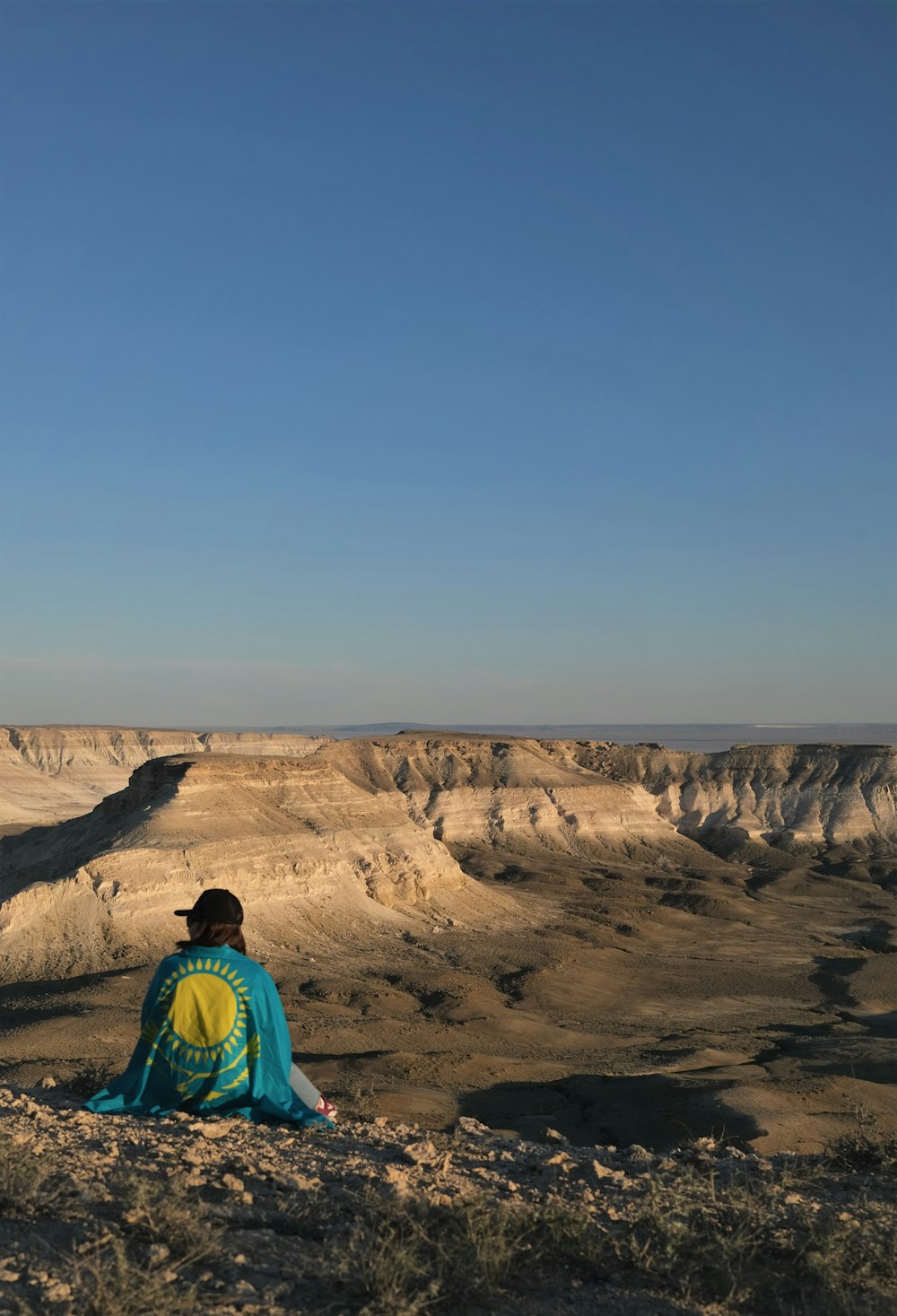 woman in blue and green jacket standing on brown rock formation during daytime