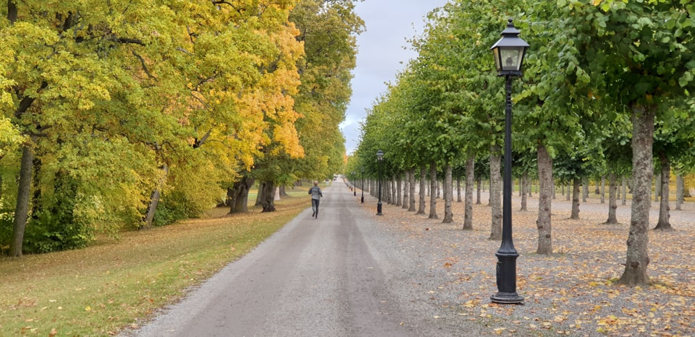 person in black jacket walking on gray concrete road during daytime