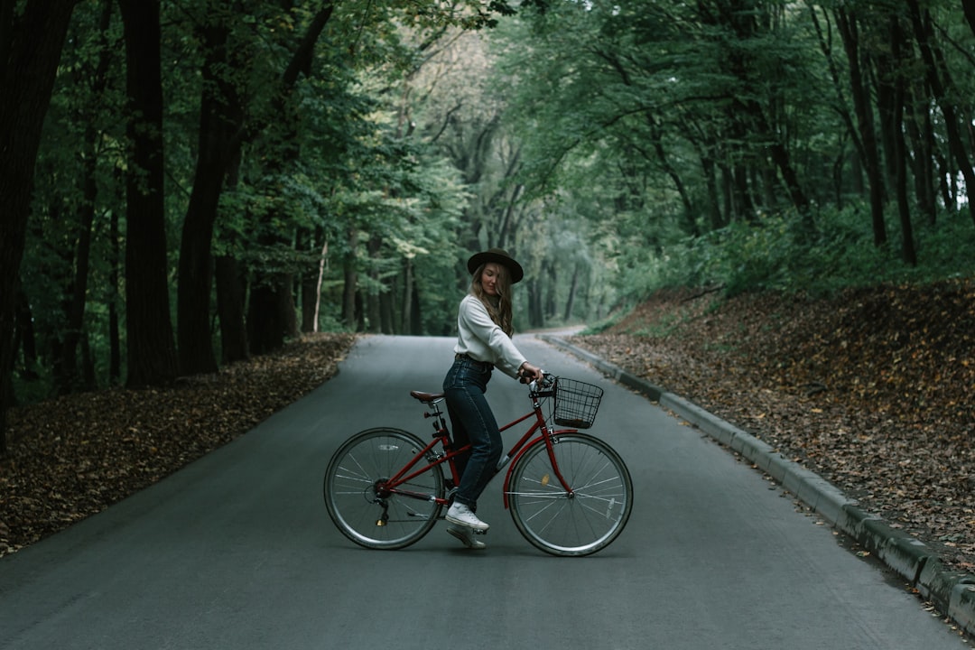 man in white shirt riding red bicycle on road during daytime