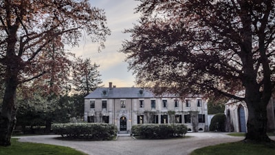 A modern, elegant mansion surrounded by lush greenery, showcasing luxury architecture.