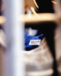 A clothing label with the text 'artclub and friends' is sewn onto a blue fabric. The image is focused on the label with blurred foreground and background, suggesting the photograph was taken in a clothing store or closet environment.