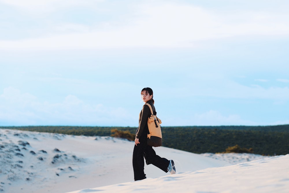 woman in black dress walking on white sand during daytime