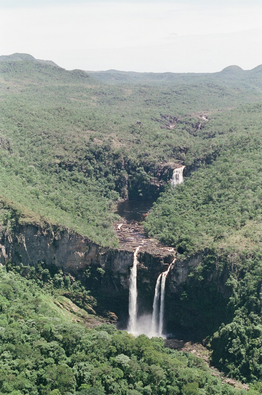 waterfalls in the middle of green trees