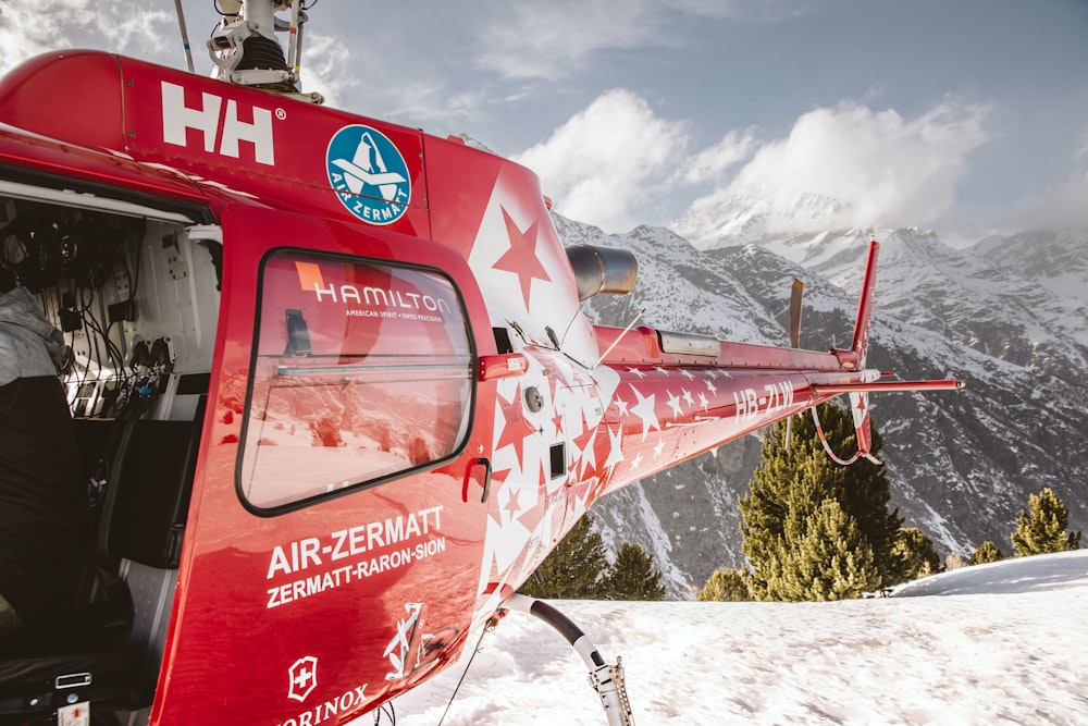 red and white helicopter flying over snow covered ground during daytime