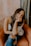 woman in white and black floral tank top and blue denim shorts sitting on brown couch