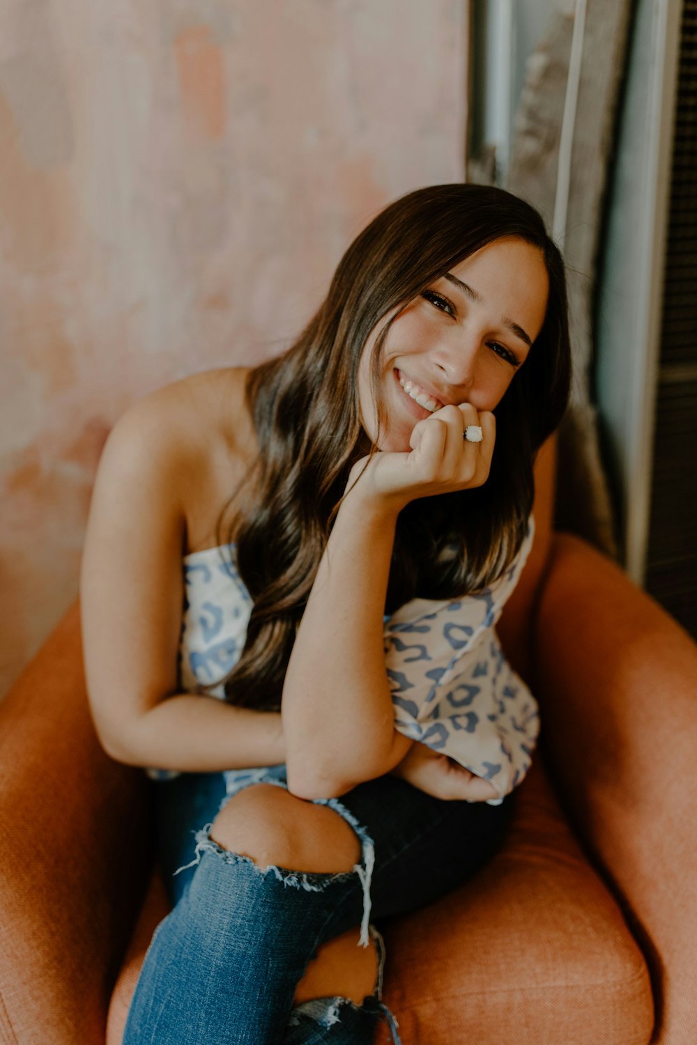 woman in white and black floral tank top and blue denim shorts sitting on brown couch