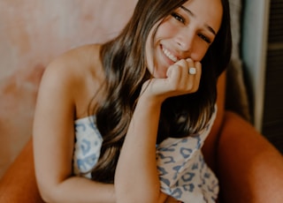 woman in white and black floral tank top and blue denim shorts sitting on brown couch