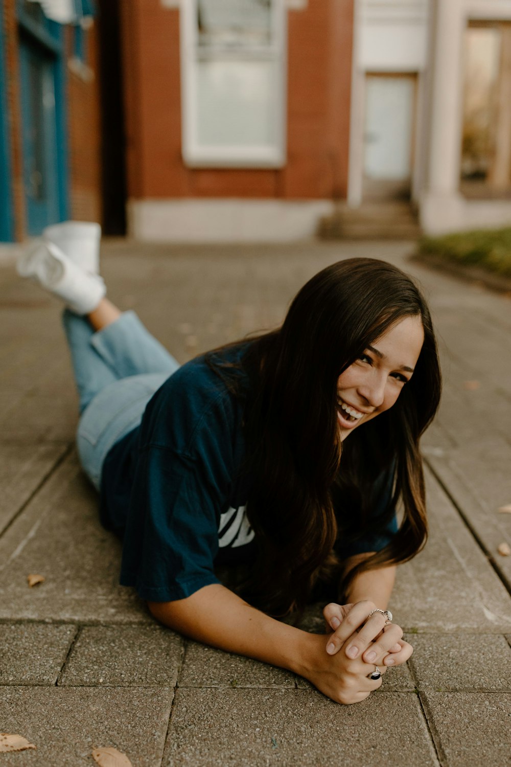 woman in blue t-shirt and blue denim jeans sitting on concrete floor during daytime