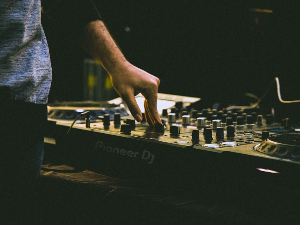 person in black t-shirt and blue denim jeans playing audio mixer