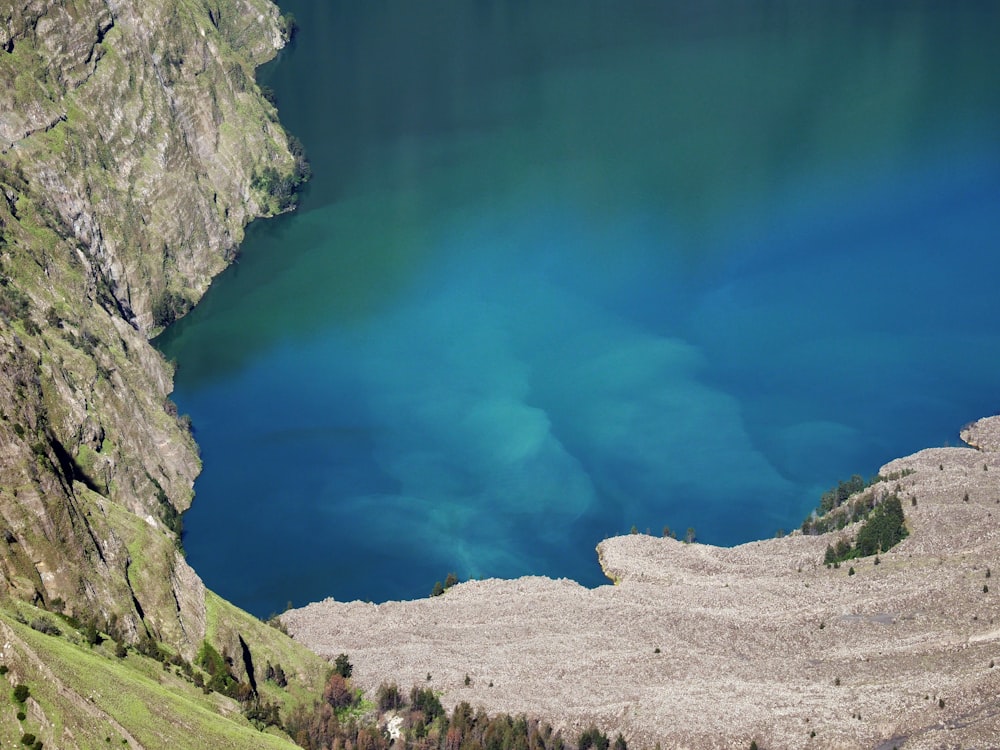 blue lake between gray rocky mountain during daytime