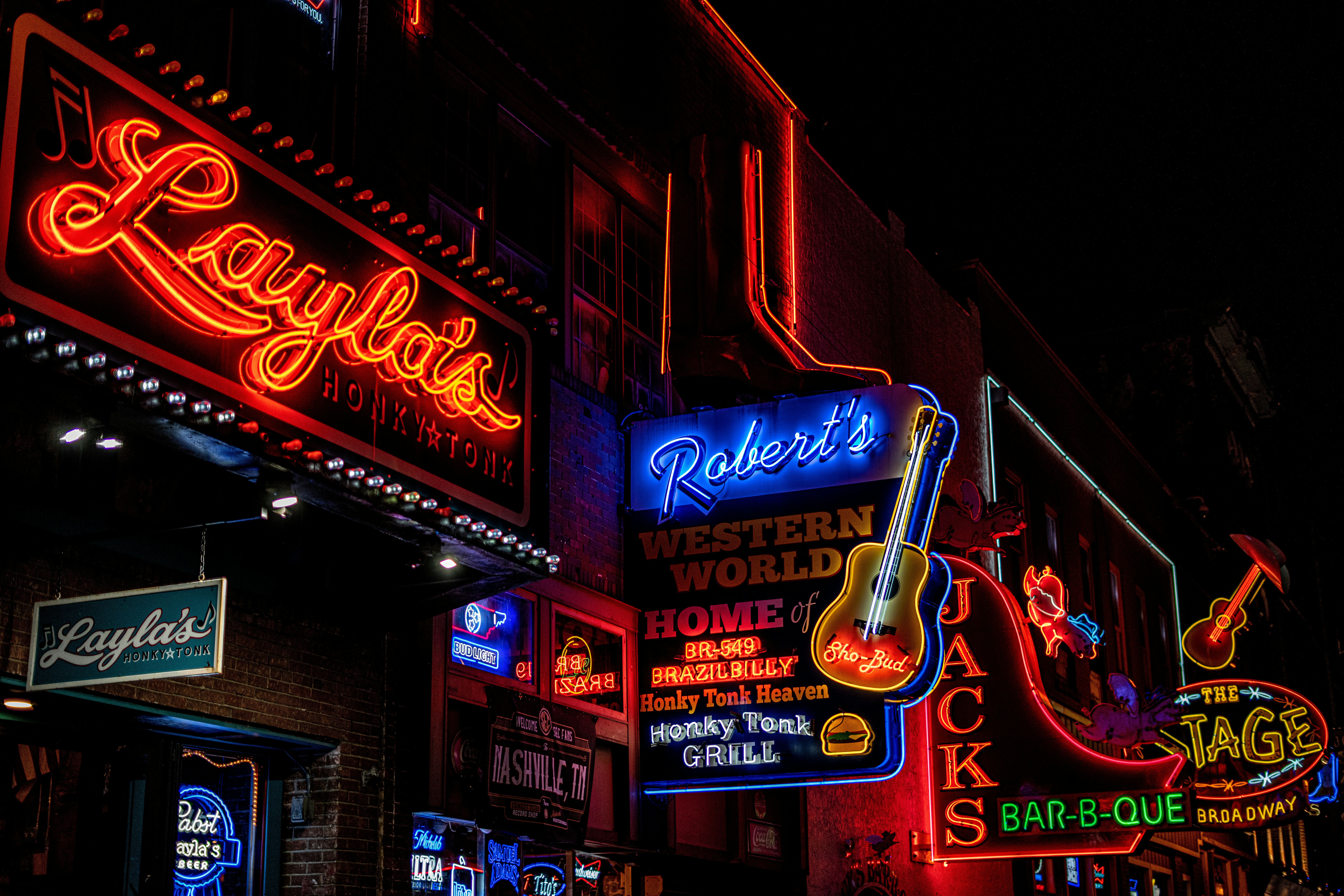 Vintage neon bar sign glowing warm red and yellow in dark roadside honky tonk, retro americana