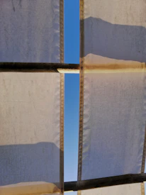 Close-up of a sleek tensile shed structure casting shadows on a sunny day.