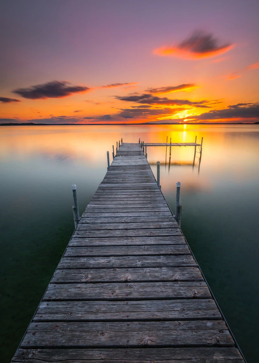 Wooden boat dock extending into calm water at sunset
