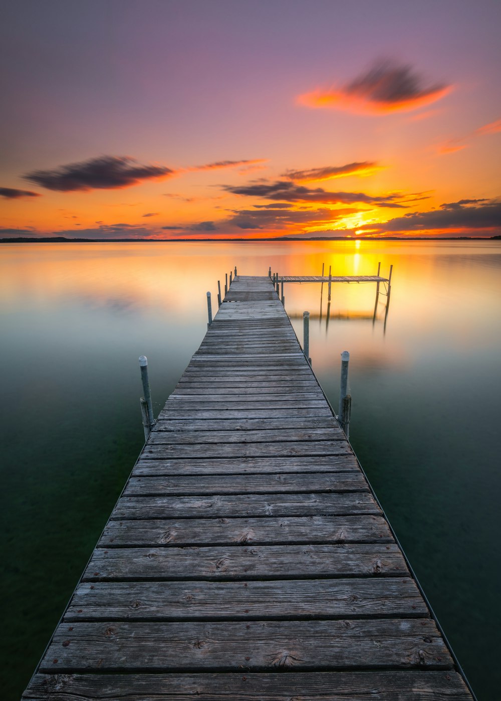 brown wooden dock on body of water during sunset