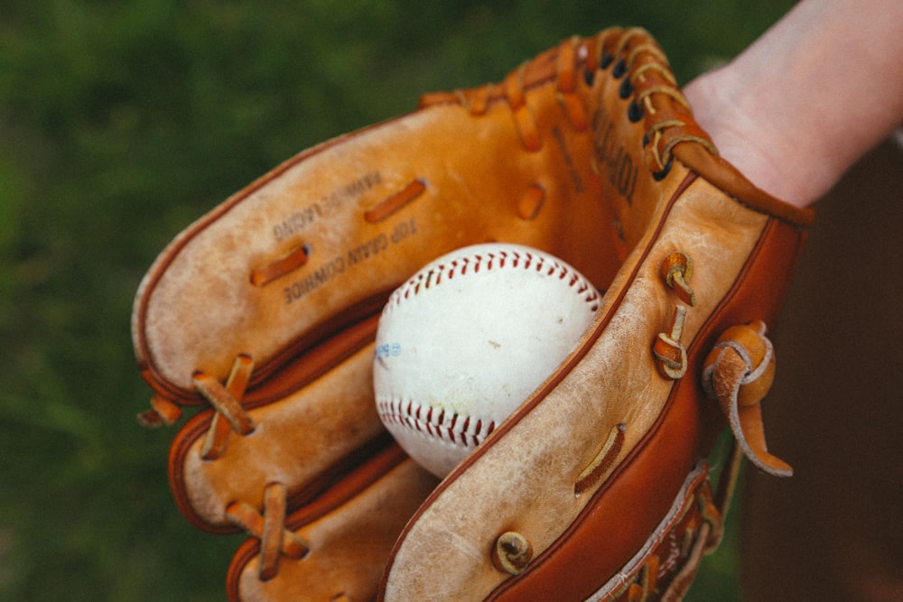 Guante de béisbol de cuero marrón con pelota de béisbol blanca