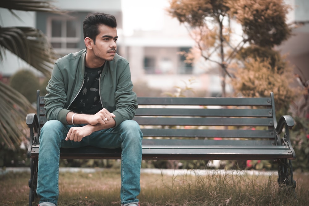 man in gray jacket sitting on brown wooden bench